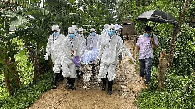 Health workers wearing PPE carry body of a Covid-19 patient at a village
