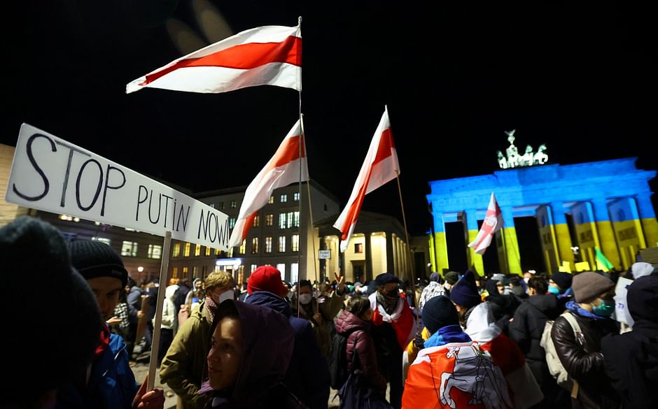 People carry Lithuanian and Latvian in front of Brandenburg Gate lit up in the colours of Ukrainian flag during an anti-war protest, after Russia launched a massive military operation against Ukraine, in Berlin, Germany on 24 February 2022