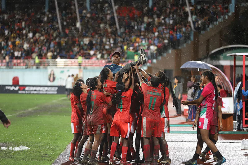 Bangladesh women's national team footballers celebrate with their coach Golam Rabbani Choton after win against Nepal in the final of SAFF Women's Championship on 19 September 2022