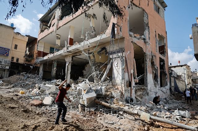 A Palestinian boy walks at the site of a damaged building following an Israeli raid in Tulkarm in the Israeli-occupied West Bank on 20 October, 2023