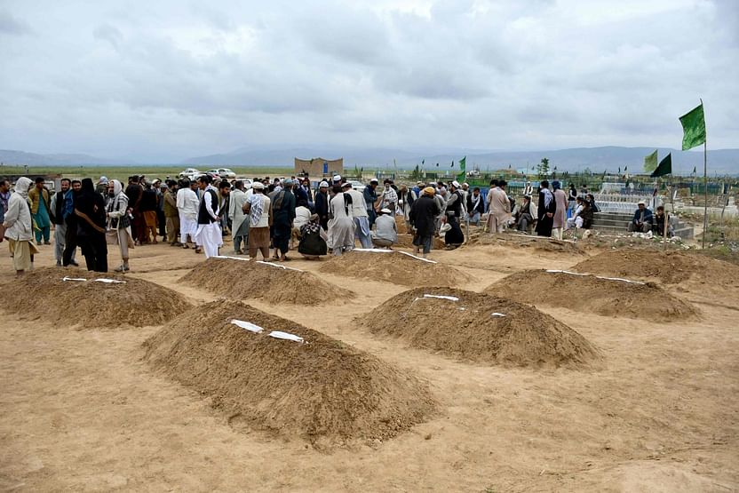 Afghan relatives offer prayers during a burial ceremony, near the graves of victim who lost their lives following flash floods after heavy rainfall at a village in Baghlan-e-Markazi district of Baghlan province on May 11, 2024.