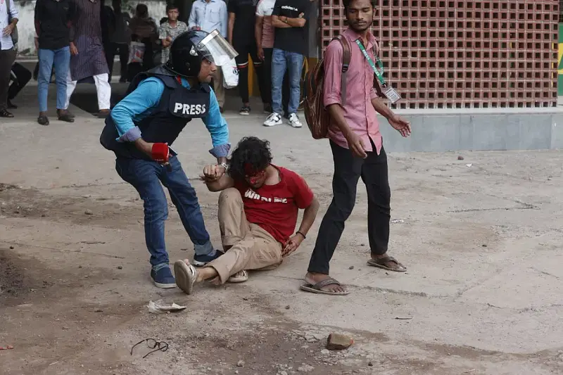 A journalist helps an injured protester during their clash with Jubo League and Chhatra League men at Science Lab in the afternoon on 16 July, 2024.