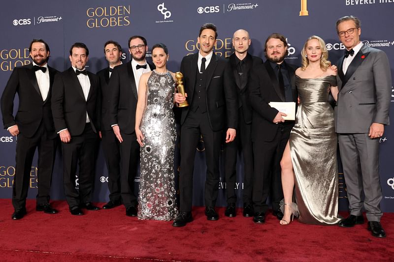 (L-R) Trevor Matthews, guest, Brian Young, guest, Felicity Jones, Adrien Brody, winner of the Best Performance by a Male Actor in a Motion Picture – Drama award for 'The Brutalist', Daniel Blumberg, Brady Corbet, Mona Fastvold, and Guy Pearce, winners of the Best Motion Picture - Drama award for 'The Brutalist', pose in the press room during the 82nd Annual Golden Globe Award at The Beverly Hilton on 5 January, 2025 in Beverly Hills, California.