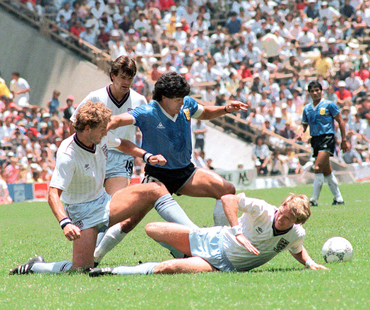 Argentinian midfielder Diego Maradona (C) dribbles past three English defenders 22 June 1986 in Mexico City during the World Cup quarterfinal soccer match between Argentina and England. Maradona scored two goals, the first one with his left hand as he jumped for the ball in front of goalkeeper Peter Shilton, as Argentina beat England 2-1. Photo: AFP