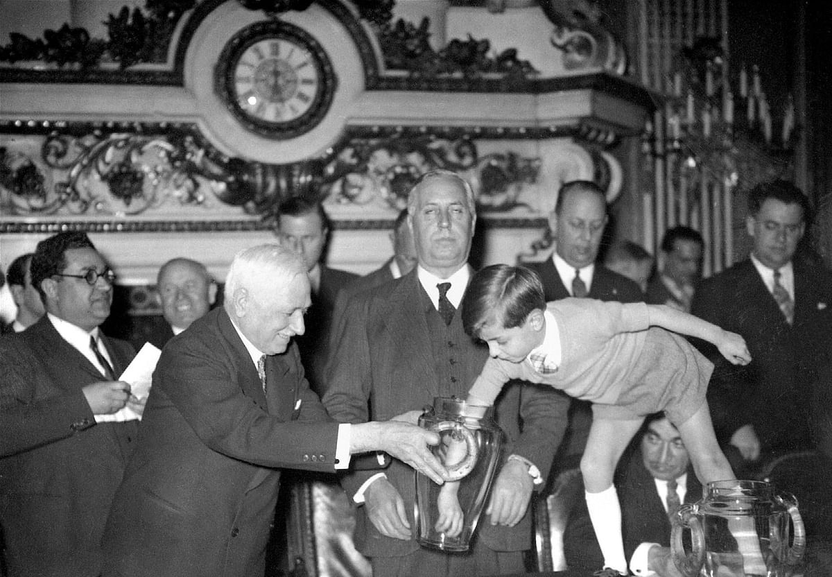 FIFA president Frenchman Jules Rimet (L), holds the urn for his grandson Yves 05 May 1938 in Paris, as he proceeds to the draw of the soccer matches for the upcoming World Cup, to be held in France (04-19 June). Standing in the middle is François de Tessan, Under-Secretary of State for Foreign Affairs. Photo: AFP