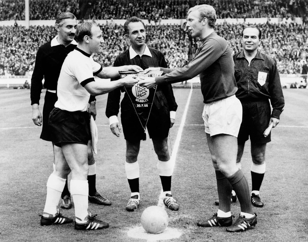 The captains of the German and English national soccer teams, Uwe Seeler (L) and Bobby Moore exchange pennants as Swiss referee Gottfried Dienst (C) looks on before the start of the World Cup final on 30 July 1966 at Wembley stadium in London. Photo: AFP
