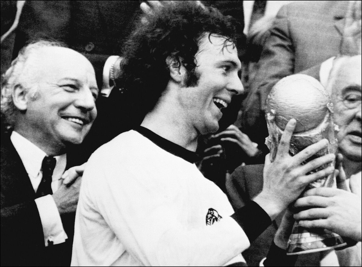 Germany's soccer star and team captain Franz Beckenbauer receives the World Soccer Cup won by his team after a 2-1 victory over Holland on 07 July 1974 at Munich's Olympic stadium as West Germany president Walter Scheel (L) applauds. Photo:  AFP