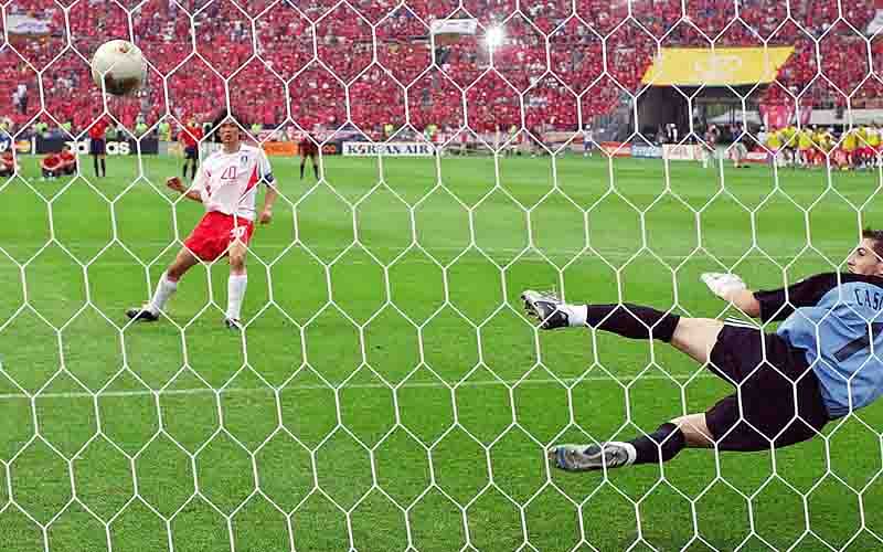 Spanish goalkeeper Iker Casillas dives as South Korean defender Hong Myung-bo (L) scores the winning goal during the quarter-final match against Spain at the 2002 FIFA World Cup Korea/Japan in Gwangju on 22 June 2002. South Korea beat Spain during the penalty shootout and will meet Germany in the semifinal match on June 25 in Seoul. Photo: AFP