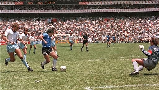 Argentinian forward Diego Armando Maradona runs past English defender Terry Butcher (L) on his way to dribbling goalkeeper Peter Shilton (R) and scoring his second goal during the World Cup quarterfinal soccer match between Argentina and England 22 June 1986 in Mexico City. Argentina advanced to the semifinals with a 2-1 victory. Photo: AFP