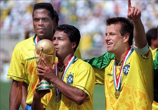 Brazilian forward Romario kisses the FIFA World Cup trophy, flanked by Ronaldao (L) and captain Dunga, after Brazil defeated Italy 3-2 in the shoot-out session (0-0 after extra time) at the end of the World Cup final on 17 July 1994 at the Rose Bowl in Pasadena. Italian Roberto Baggio missed his penalty kick to give Brazil its fourth World Cup title after 1958, 1962 and 1970. Photo: AFP