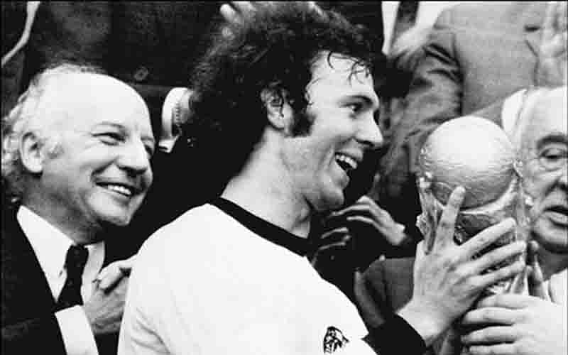 Germany's soccer star and team captain Franz Beckenbauer receives the World Soccer Cup won by his team after a 2-1 victory over Holland 07 July 1974 at Munich's Olympic stadium, as West Germany president Walter Scheel (L) applauds. Photo: AFP