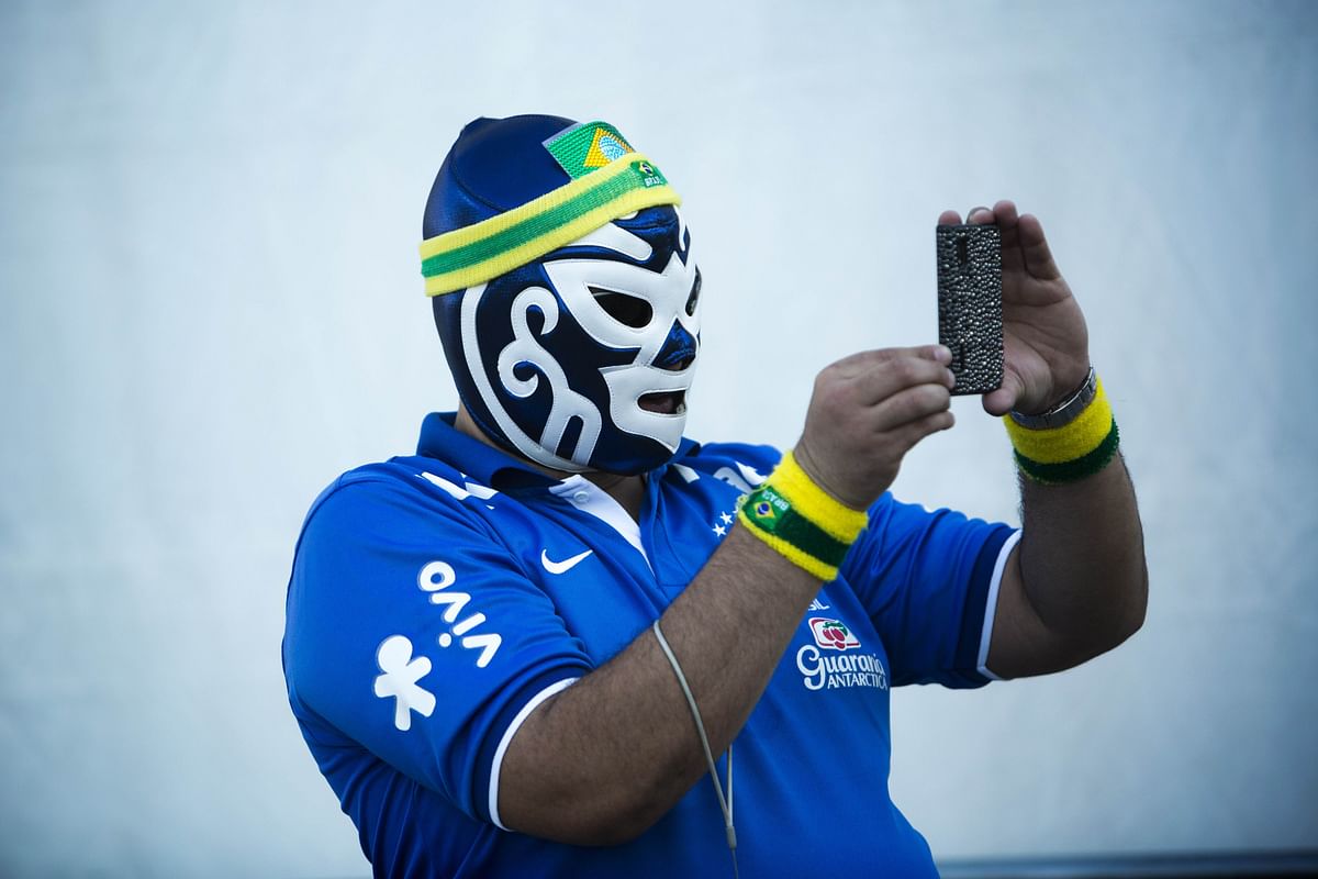 A Brazilian fan wearing a mask, takes pictures outside the Corinthians Arena in Sao Paulo prior to the start of the Group A opening football match between Brazil and Croatia during the 2014 FIFA World Cup on June 12, 2014. Photo: AFP