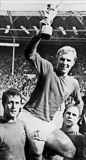 England's national soccer team captain Bobby Moore is carried by his teammates, Geoff Hurst (L) - who scored three goals - and Ray Wilson, as he holds aloft the Jules Rimet trophy following England's victory over Germany. AFP