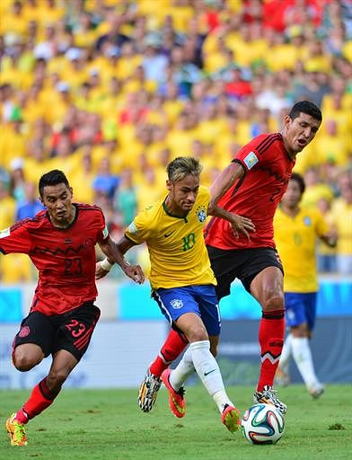 Brazil's forward Neymar (C) controls the ball between Mexico's midfielder Vazquez (L) and Mexico's defender Rodriguez (R) during a Group A match against Mexico in Fortaleza during the 2014 FIFA World Cup on June 17, 2014. AFP
