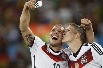 Germany's midfielder Bastian Schweinsteiger (R) and Germany's forward Lukas Podolski (C) take a 'selfie' after their victory in extra-time in the final football match between Germany and Argentina for the FIFA World Cup at The Maracana Stadium in Rio de Janeiro on July 13, 2014. AFP