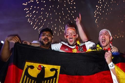 German fans celebrate during a firework after an outdoor screening near the Brandenburg Gate in Berlin, on July 13, 2014, as Germany won the FIFA World Cup 2014 final football match against Argentina played in Brazil. More than 200,000 Germany fans thronged in central Berlin for the World Cup final, turning an avenue behind the Brandenburg Gate into a sea of black, red and gold flags. Germany won 1-0. AFP