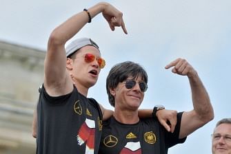 German national football team coach Joachim Loew (r) and player Julian Draxler cheer as they ride in an open-deck bus to Berlin's landmark Brandenburg Gate to celebrate their FIFA World Cup title. AFP