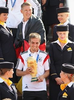 German national football team's defender Philipp Lahm (bottom) holds the trophy as he and Germany's midfielder Bastian Schweinsteiger (up) get off the airplane at Berlin airport Tegel on July 15, 2014, as they arrive from Brazil after they won the FIFA World Cup 2014. AFP