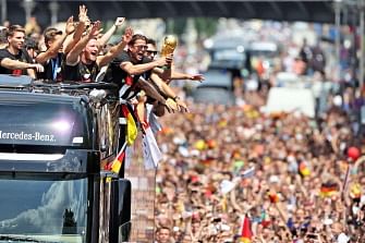 German national football team players cheer as they ride in an open-deck bus to Berlin's landmark Brandenburg Gate to celebrate their FIFA World Cup title. Germany won their fourth World Cup title, after 1-0 win over Argentina on July 13, 2014 in Rio de Janeiro in the FIFA World Cup Brazil final game. AFP