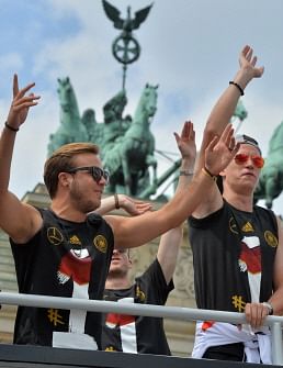 German national football team players Mario Goetze (L) and Julian Draxler (R) cheer as they ride in an open-deck bus to Berlin's landmark Brandenburg Gate to celebrate their FIFA World Cup title. AFP