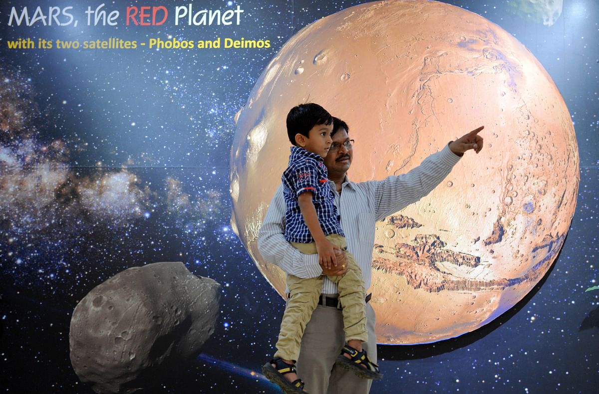 A father and his son look at information about planet Mars on a poster put up at the Nehru Planetarium as a special preview on India's Mars Orbiter Mission, in Bangalore. Photo: AFP
