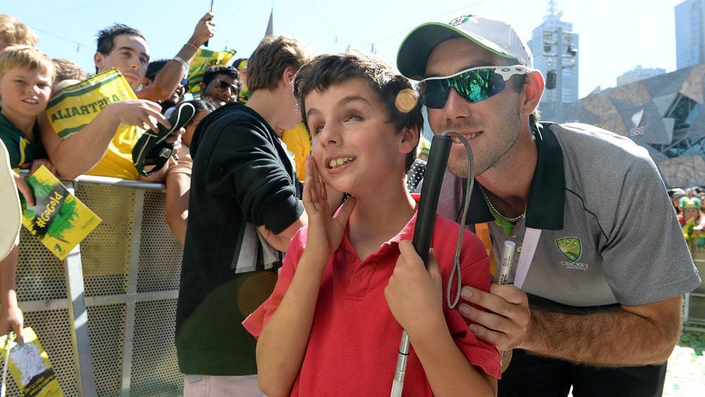 Australian cricketer Glenn Maxwell obliges visually handicapped fan Christian Kouroumihalis with a photograph during a public event to celebrate their victory in the world cup in Melbourne on March 30, 2015. Photo:AFP