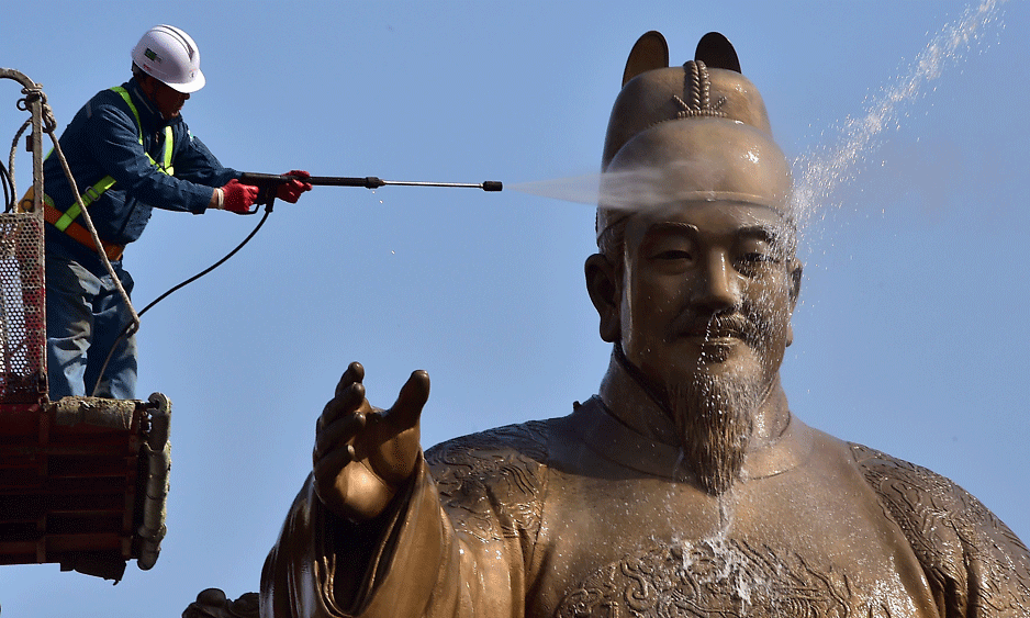 A South Korean worker uses water to wash a bronze statue of King Sejong, the 15th-century Korean king, during a street and park clean-up event for the spring at Gwanghwamun plaza in Seoul on April 13, 2015. Photo: AFP