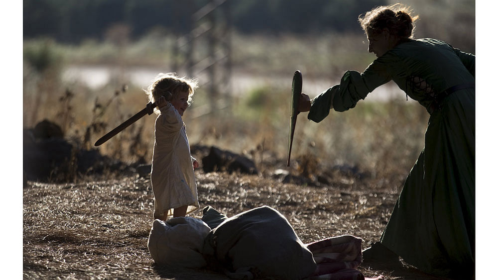 An enthusiast wearing a costume plays with her child during a re-enactment of a decisive Crusaders battle in northern Israel