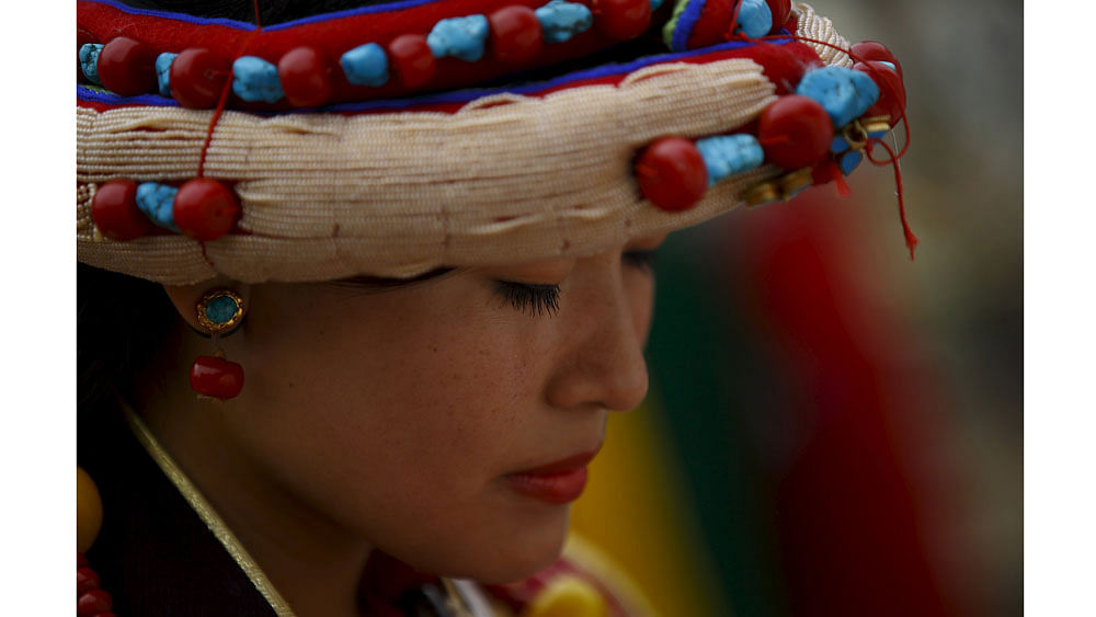 A Tibetan woman in traditional attire offers prayers in front of a portrait of Dalai Lama during his 80th birthday celebrations in Kathmandu July 6, 2015. Photo: Reuters