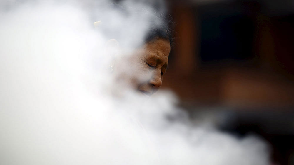 Smoke rise as a Tibetan woman burns incense while offering prayers during a function organized to mark the 80th birthday celebration of Dalai Lama in Kathmandu July 6, 2015. Photo: Reuters