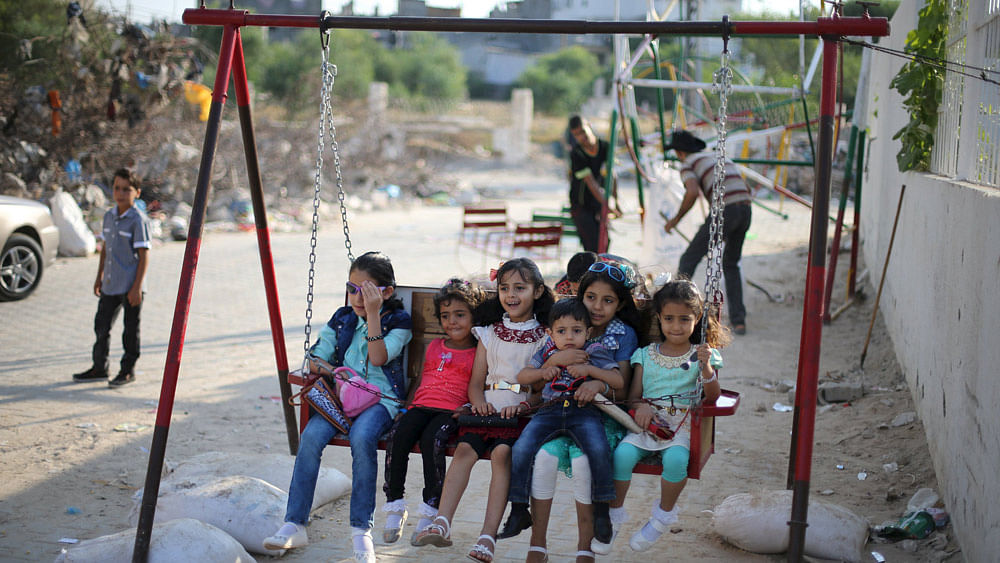 Palestinian children play on a swing near the ruins of houses, that witnesses said were destroyed by Israeli shelling during a 50-day war last summer, on the first day of Eid al-Fitr holiday. Photo: Reuters