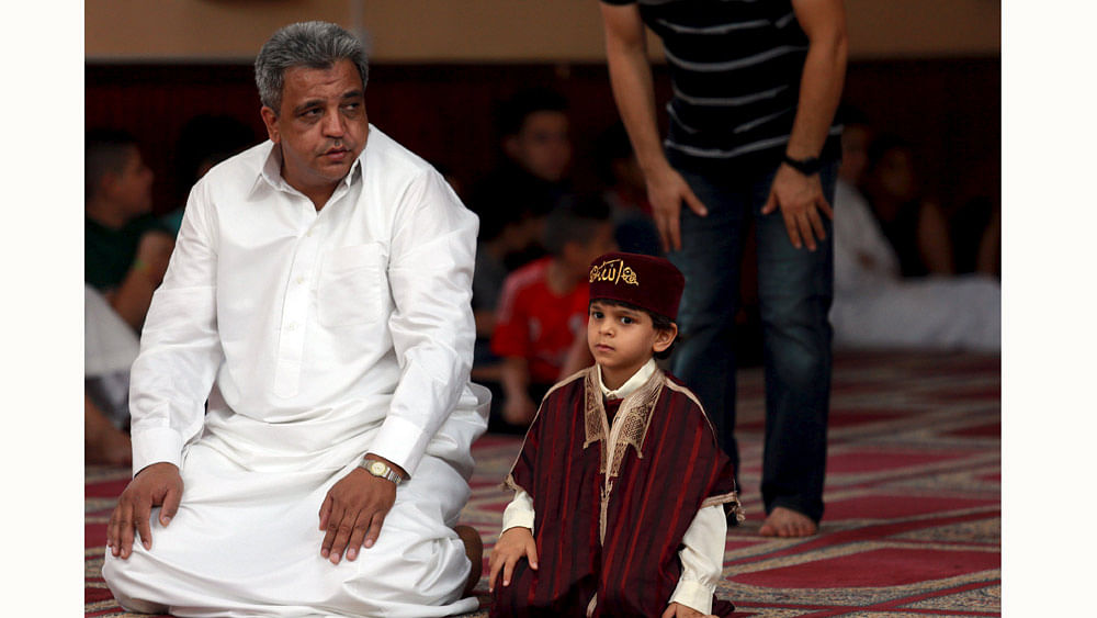 A boy waits for prayers with his father at a mosque during Eid al-Fitr to mark the end of Ramadan in Benghazi, Libya July 17, 2015. Photo: Reuters