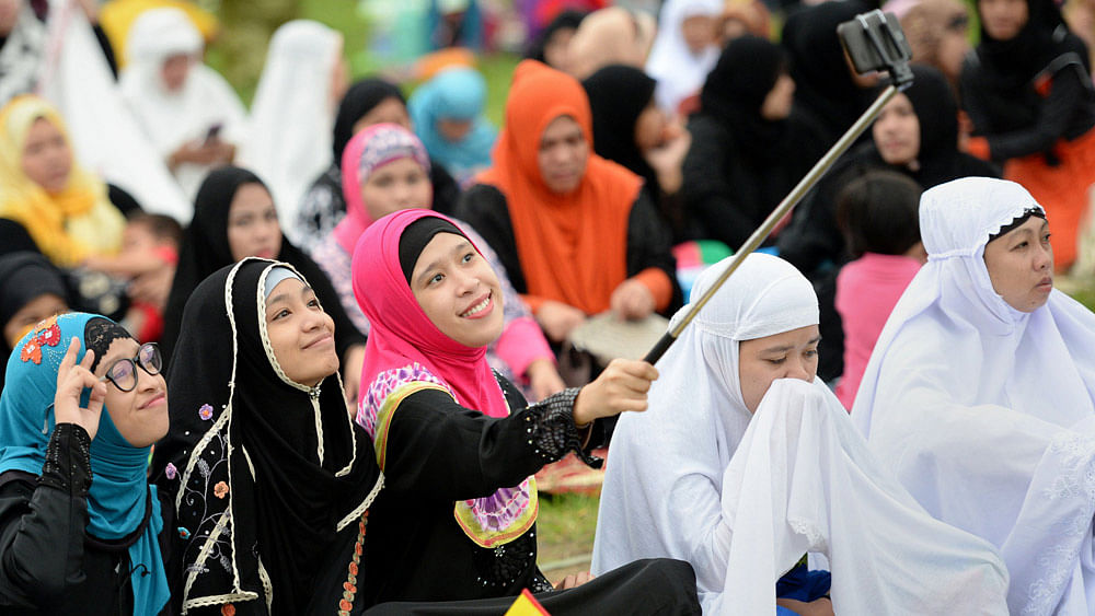 oung Muslim devotees take a "selfie" prior to Friday prayers to mark the end of the holy month of Ramadan and the start of Eid al-Fitr at a park in Manila on July 17, 2015.Photo:AFP