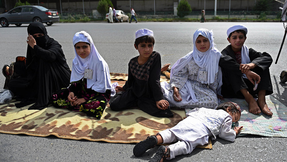 An Afghan woman and children beg for alms as other leave after offering prayers at the start of the Eid al-Fitr holiday. Photo:AFP