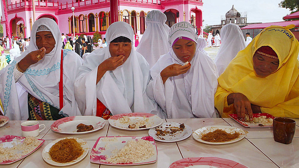Filipino Muslims eat a meal after attending the morning prayers of Eid al-Fitr holiday. Photo: Reuters