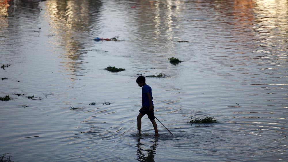 A boy drags a magnet tied on a rope as he searches for coins offered by the devotees at the Bagmati river during the Rishi Panchami festival, in Kathmandu, Nepal September 18, 2015. Photo: Reuters