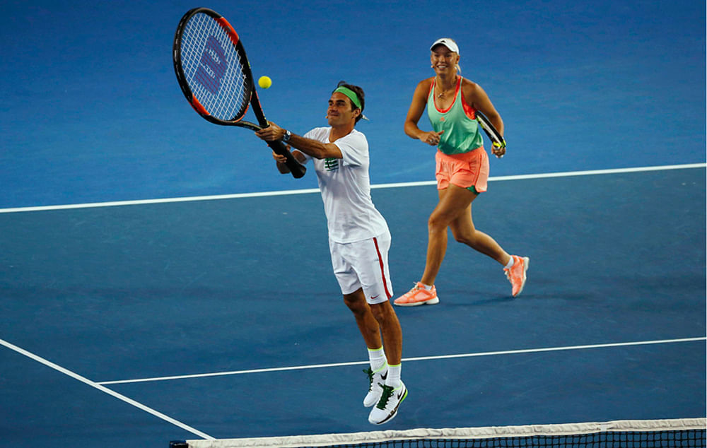 Switzerland`s Roger Federer jumps to hit the ball with a giant tennis racket as Denmark`s Caroline Wozniacki watches during Kids Tennis Day at Melbourne Park, Australia, January 16, 2016. Reuters