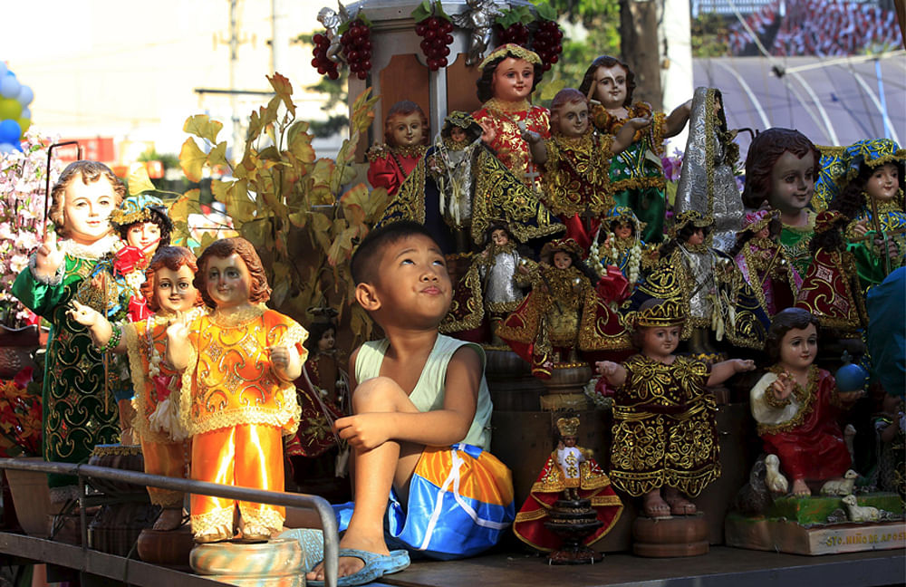 A boy looks up while surrounded by Sto. Nino (infant Jesus) replicas during a procession in Manila January 16, 2016, a day before the annual of the feast day of Sto. Nino on Sunday. Reuters