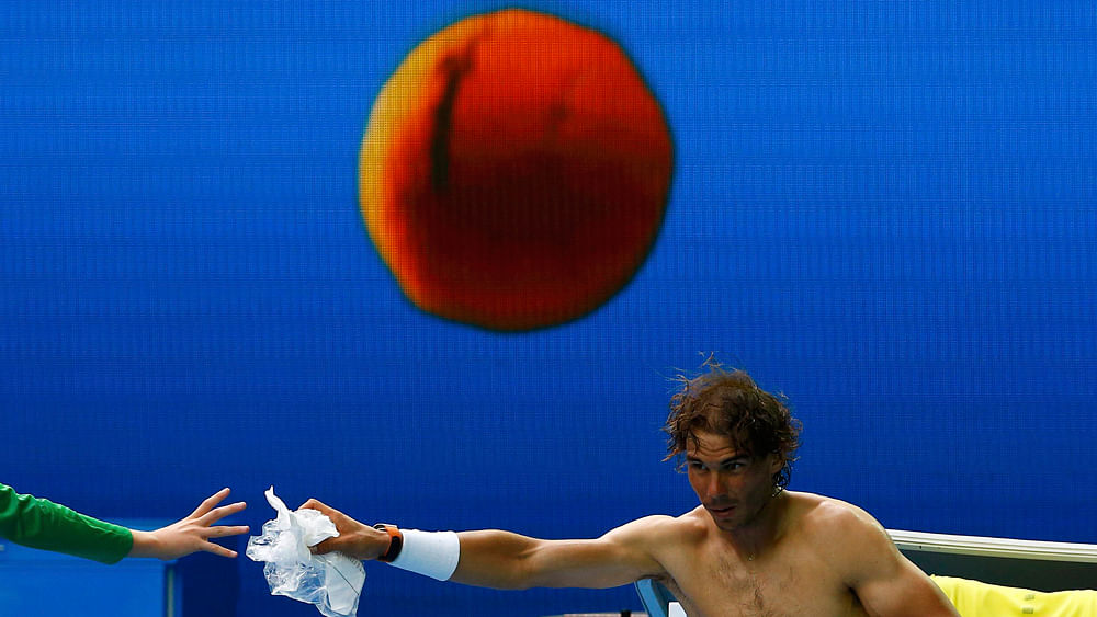 Spain`s Rafael Nadal hands plastic to a ball boy as he changes shirt during his first round match against Spain`s Fernando Verdasco at the Australian Open tennis tournament at Melbourne Park, Australia, January 19, 2016. Photo: Reuters