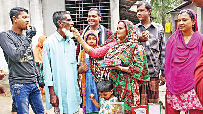 Mother Karimunnesa offers sweets to her husband Ahmed Gazi, father of Mahfuza, celebrating the gold wining of their daughter at their Abhaynagar house in Jessore on Tuesday.  Prothom Alo photo