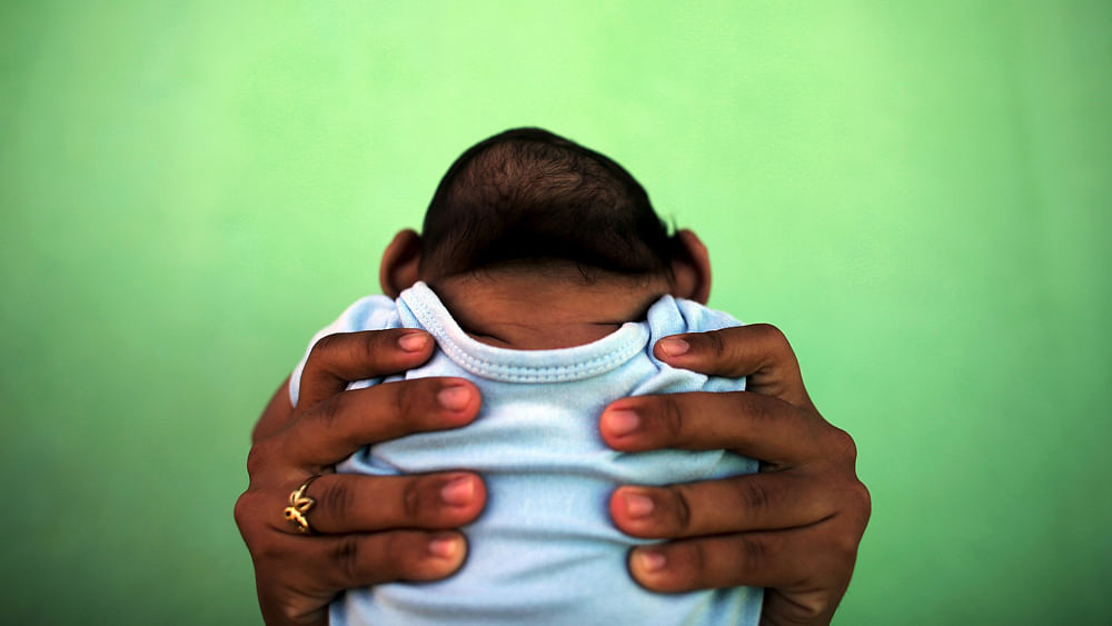 Jackeline, 26, holds her son who is 4-months old and born with microcephaly, in front of their house in Olinda, near Recife, Brazil, February 11, 2016. Photo: Reuters