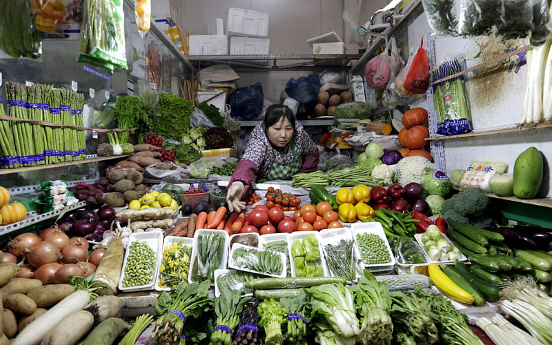 A vendor reaches out for vegetables at her shop in a market in Beijing, February 18, 2016. Reuters