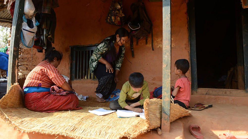 Nepalese migrant worker Sunita Magar (C), who was trafficked to Syria, working next to her mother (L), son Bipin Magar (2nd R) and daughter Elina Magar (R) at their house in Dhadhing district, some 100 kilometres west of Kathmandu. Photo: AFP