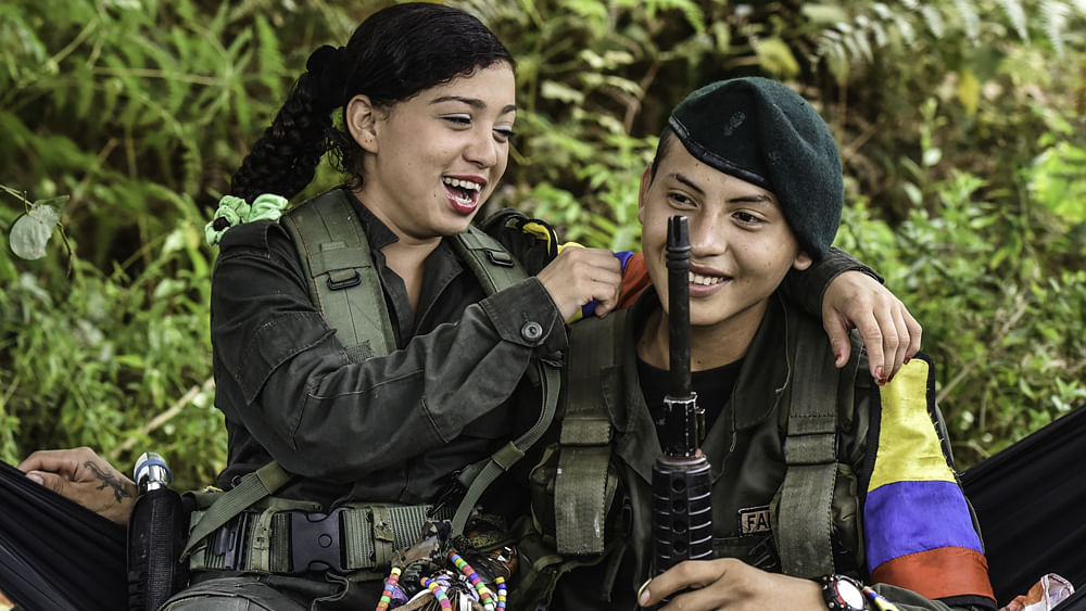 A couple of members of the Revolutionary Armed Forces of Colombia (FARC) jokes at a camp in the Magdalena Medio region, Antioquia department, Colombia on 18 February 2016. FARC leader Timoleon Jimenez confirmed that his men were attacked by the Colombian army as they went to received one of the commanders who takes part in the Havana peace talks. Photo: AFP