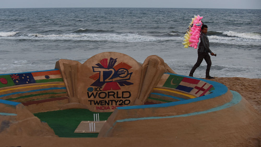 An Indian cotton candy vendor walks past a sand sculpture designed with an ICC World Twenty20 India 2016 cricket tournament theme on the beach in Chennai on 15 March 2016. Photo: AFP
