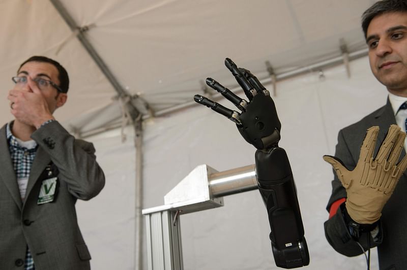 Exhibitors from Johns Hopkins Applied Physics Laboratory stand with a robotic hand during the Defense Advanced Research Projects Agency (DARPA) Demo Day at The Pentagon on 11 May in Washington, DC. Photo: AFP