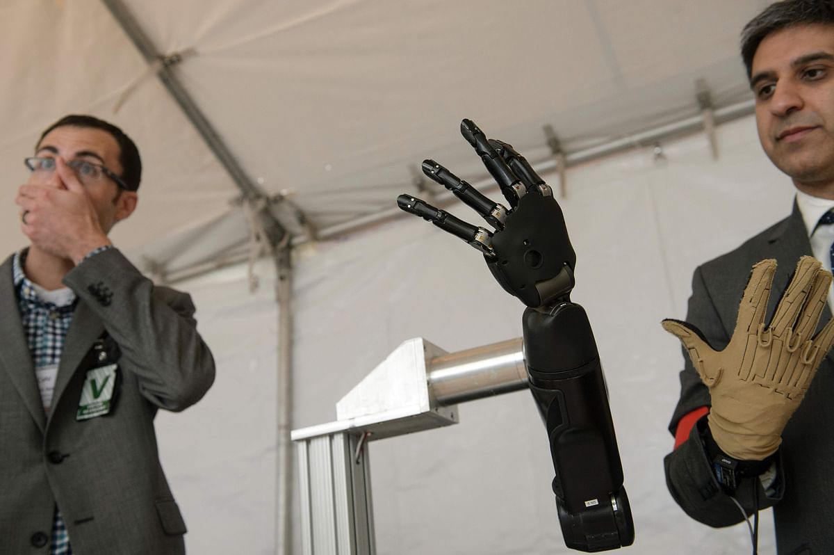 Exhibitors from Johns Hopkins Applied Physics Laboratory stand with a robotic hand during the Defense Advanced Research Projects Agency (DARPA) Demo Day at The Pentagon on 11 May in Washington, DC. Photo: AFP