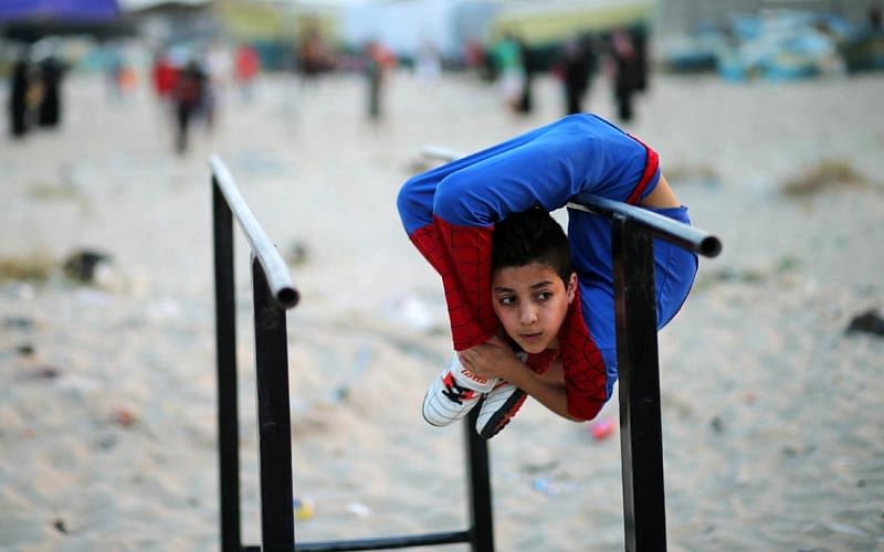 Palestinian boy Mohamad al-Sheikh, 12, who is nicknamed `Spiderman` and hopes to break the Guinness world records with his bizarre feats of contortion, demonstrates acrobatics skills on a beach in Gaza City June 2, 2016. Photo: Reuters