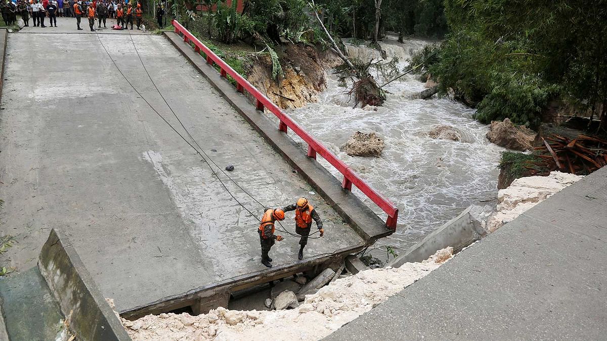 Members of Guatemalan emergency commission (CONRED) stand at a bridge that collapsed after heavy rains brought by Hurricane Earl at Menchor de Mencos, Guatemala, August 4, 2016. Photo: Reuters