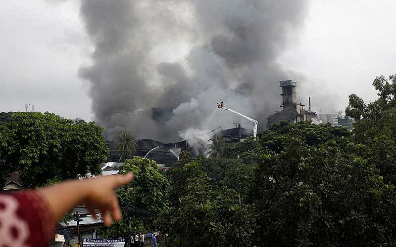 A woman points to a garment packaging factory on fire outside of Dhaka, Bangladesh, September 10, 2016. Photo: Reuters
